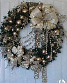 a wreath is hanging on the front door with pearls, bows and other holiday decorations