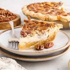 a slice of pecan pie on a plate with a fork and two other pies in the background