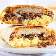 two breakfast burritos stacked on top of each other, one filled with eggs and sausage