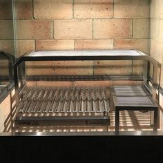 an empty display case in front of a brick wall with metal slats on it