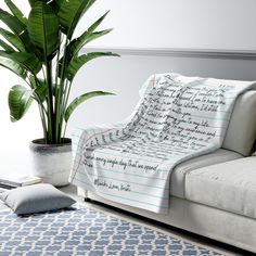 a living room with a couch, potted plant and rug on the floor in front of it