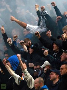 a group of people standing around each other with their hands in the air and fists raised