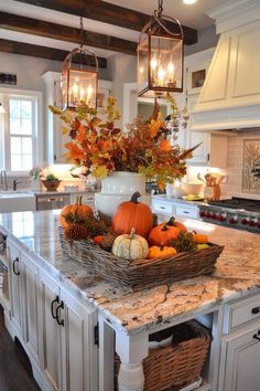 a kitchen island topped with lots of pumpkins and gourmet fruit in baskets