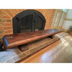 a wooden bench sitting on top of a hard wood floor next to a brick fireplace