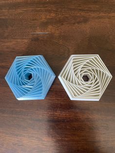 two hexagonal objects sitting on top of a wooden table