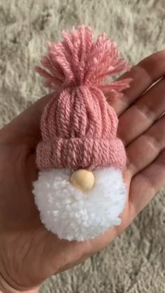 a hand holding a small pink and white knitted hat