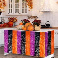 a kitchen island decorated with orange and purple streamers, pumpkins and gourds