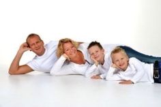 an image of a family posing for a photo on the white floor with their arms around each other