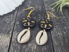 "These gorgeous dangle earrings feature genuine off-white sliced moneta cowrie shells dangling beneath 20mm round carved black and gold acrylic beads an etched Afrocentric abstract pattern. Aching for acrylics? Check out the rest of my acrylic jewelry here: https://etsy.me/2IadiWZ Throughout Africa and the Americas, cowrie shells have historically been viewed as symbols of womanhood, fertility, and prosperity. Check out my other cowrie shell jewelry here: https://etsy.me/2VQS0r0 These earrings m Artisan Black Jewelry For The Beach, Handmade Black Earrings For Beach, Black Dangle Jewelry For Beach, Black Drop Earrings For Summer, Black Shell Jewelry For Gifts, Black Shell Jewelry Gift, Black Shell Jewelry As A Gift, Handmade Black Jewelry For Vacation, Cowrie Shell Earrings For Gifts