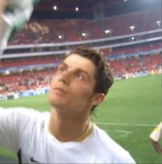 a man holding up a wine glass in front of his face at a soccer game