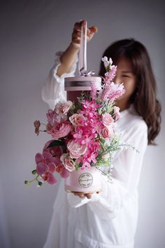 a woman holding a bouquet of flowers in front of her face with a camera attached to it