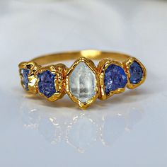 a gold ring with blue and white stones on it's sides, sitting on a table