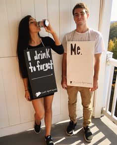 a man and woman standing next to each other while drinking from water bottles in front of a sign