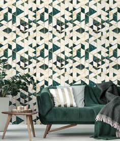 a green couch sitting in front of a wall with geometric designs on it and a table next to it