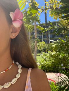 a close up of a person wearing a necklace with flowers in her hair and an earring