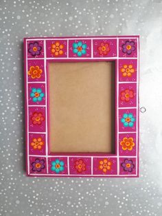 a pink frame with flowers painted on the side and dots in the background, sitting on a table