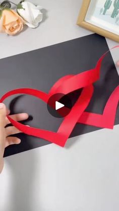 someone cutting out a paper heart with scissors