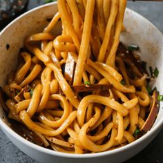 a bowl full of noodles with chopsticks sticking out of the top and sauce in the middle