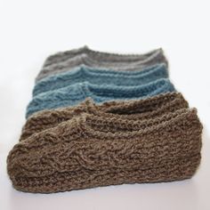 three crocheted hats sitting next to each other on a white surface, one is blue and the other is brown