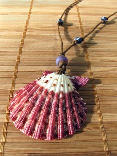 Ready for the Beach? Beautiful Purple Scallop shell is simply stunning!  This bold magenta pattern is the shell's natural color!  The front is very shiny,  it may have been polished or given a clear gloss finish.  I have topped it with one translucent matte bluish-purple glass pony bead and added three asymmetrically knotted white-striped opaque blue/purple glass E-beads.  I have strung and knotted them on waxed brown cotton cord creating a lightweight and comfortable adjustable necklace that is Handmade Pink Shell Necklace For Vacation, Handmade Pink Shell Necklace For Beach, Summer Gift Pink Shell Necklace, Pink Shell Strand Jewelry, Pink Shell-shaped Necklace For Beach, Handmade Purple Beaded Necklaces For Beach, Bohemian Shell With Colorful Beads For Gift, Pink Bohemian Shell Jewelry, Beachy Shell Beaded Necklaces As Gifts