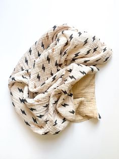 a white scarf with black arrows on it sitting on a white surface, next to a pair of scissors