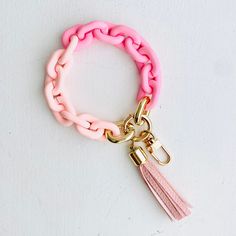 the pink and gold bracelet has a tasseled charm on it's end