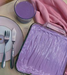 a purple cake is sitting on a plate with silverware