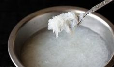 a spoon full of rice is being held up by someone's hand in a silver bowl