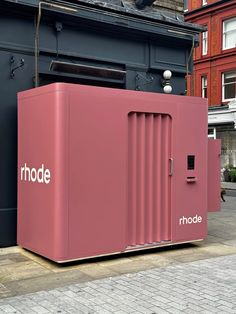 a large pink box sitting on the side of a road next to a tall building