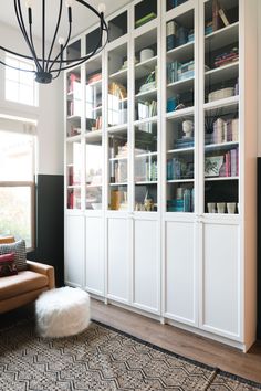 a living room filled with lots of furniture and bookshelves next to a window