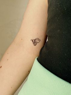 a woman's arm with a small tattoo of a bee on the back of her left arm