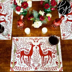 the table is set with red and white placemats, candles, and flowers