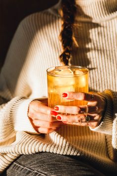 a woman holding a glass of tea in her hands