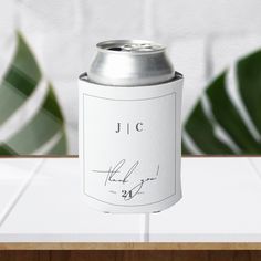 a can of jlc is sitting on a table next to some green leafy leaves