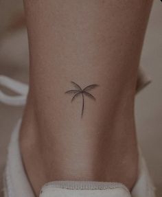 a small palm tree tattoo on the back of a woman's leg and ankle