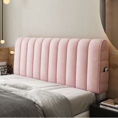 a pink headboard on top of a bed next to a night stand and lamp