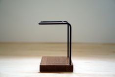 a wooden stand with a black metal object on it's end and a white wall in the background