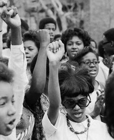 black and white photograph of people raising their hands in the air with other people standing around