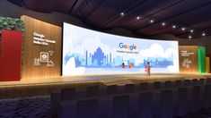 a woman standing on stage in front of a large screen with the google logo above it