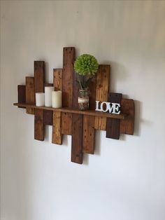 a wooden shelf with some candles and a vase on top of it that says love