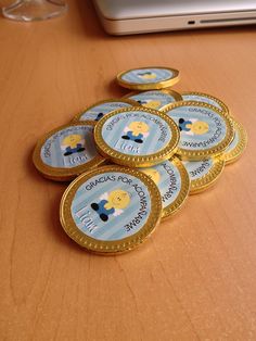 a pile of gold coins sitting on top of a wooden table next to a laptop