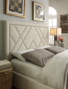 a bed with white linens and pillows in a bedroom next to two pictures on the wall