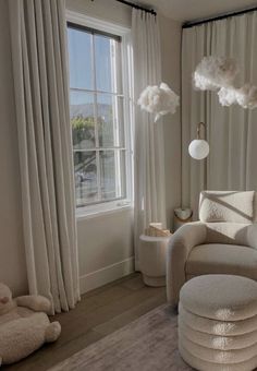 a living room filled with lots of furniture and white drapes on the windowsill