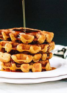 a stack of waffles on a plate with syrup drizzled over them