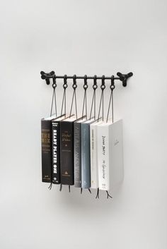 three books are hanging on the wall with black metal brackets holding them up to hold them