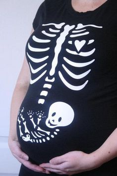 a pregnant woman wearing a skeleton t - shirt and holding her belly in front of the camera