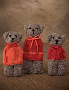 three knitted teddy bears in sweaters and hats, one wearing an orange scarf