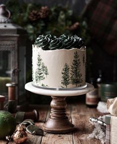 a white cake with green frosting sitting on top of a wooden table next to christmas decorations