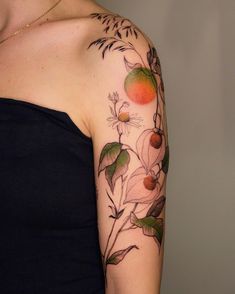 a woman's arm with flowers and fruit on the back of her left arm