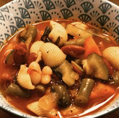 a bowl filled with pasta and vegetables on top of a table